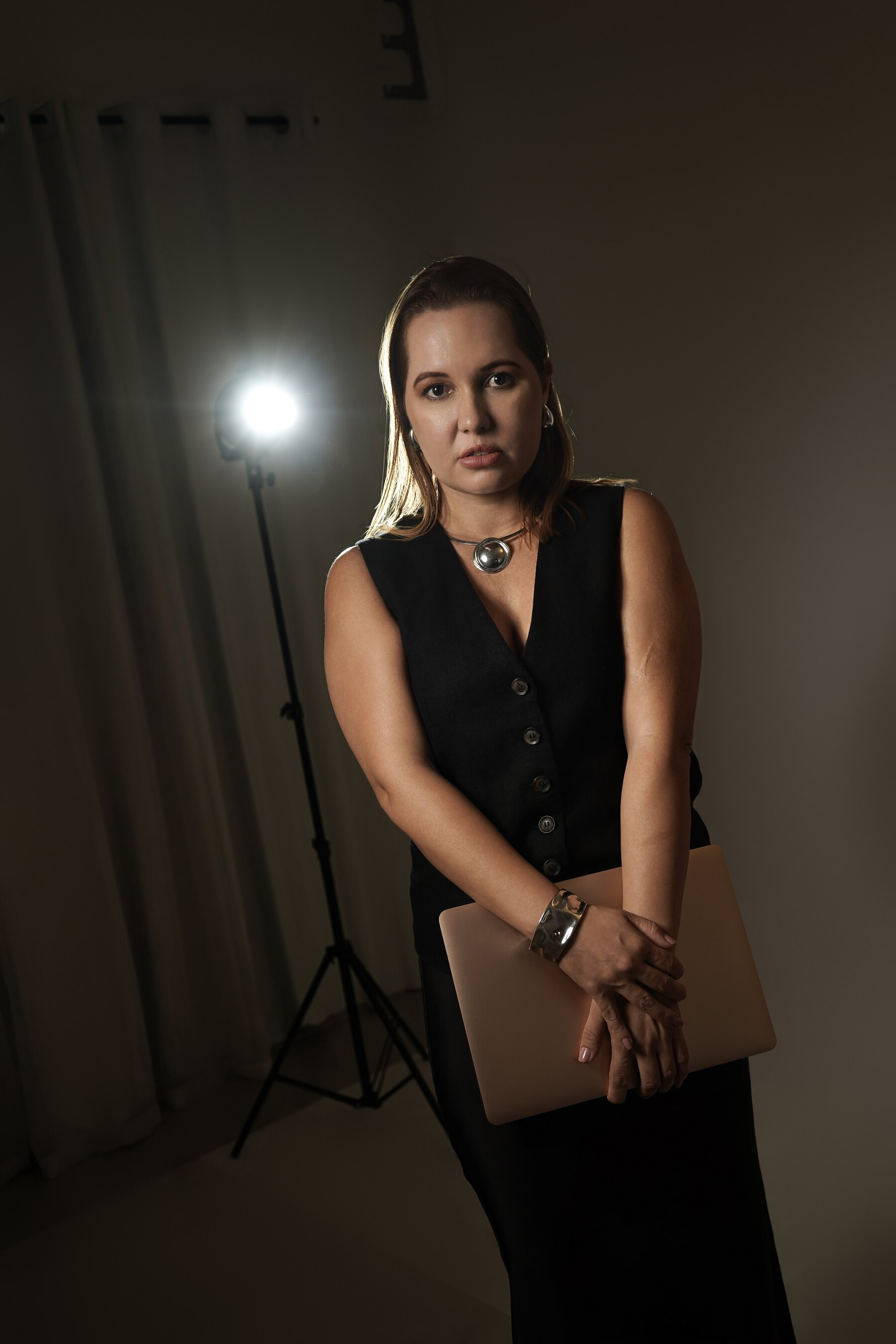 Monique Laira em bastidor de criação com notebook e iluminação de estúdio